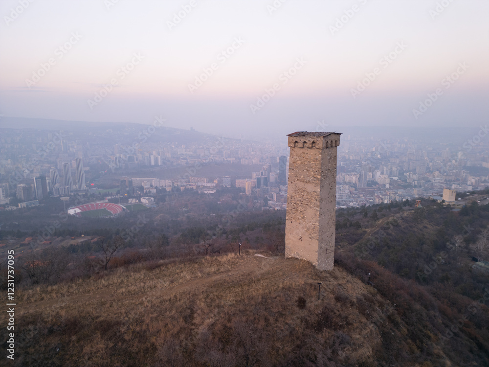 Ancient Georgian tower against the backdrop of modern Tbilisi city at dusk. Ancient Georgian tower against the backdrop of modern Tbilisi city at dusk.