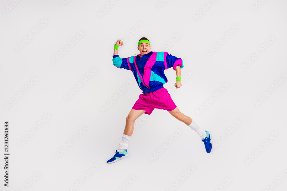 Fototapeta premium Energetic young man in retro sportswear jumping with joy against a white backdrop