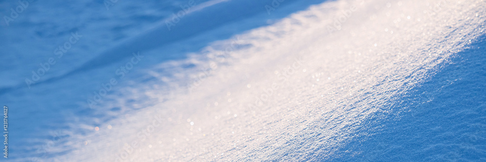 Obraz premium Beautiful winter background with snowy ground. Natural snow texture. Wind sculpted patterns on snow surface. Wide panoramic texture for background and design. Closeup top view with copy space.
