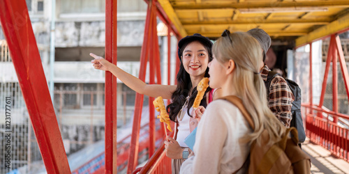 Diverse group of friends enjoying street food while exploring a vibrant city, sharing laughter and travel experiences on a colorful bridge. photo