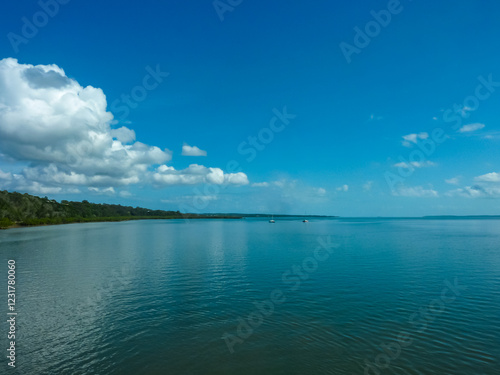 Tranquil seascape in Cooloola, Australia. Calm, reflective waters near the Great Sandy National Park. Two sailboats glide peacefully in the distance, adding sense of serenity to the vast, blue scene. photo