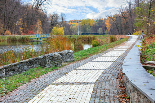 Obraz na płótnie Walking along the tranquil lakeside path surrounded by autumn colors and gentle clouds w salonie