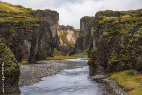 Le canyon de Fjaðrárgljúfur en Islande, avec ses falaises de basalte couvertes de mousse et sa rivière sinueuse. Un paysage féerique où la nature brute et l’eau sculptent un décor spectaculaire.