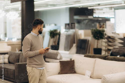 a man in a furniture store with a phone looking to buy a sofa for the living room
