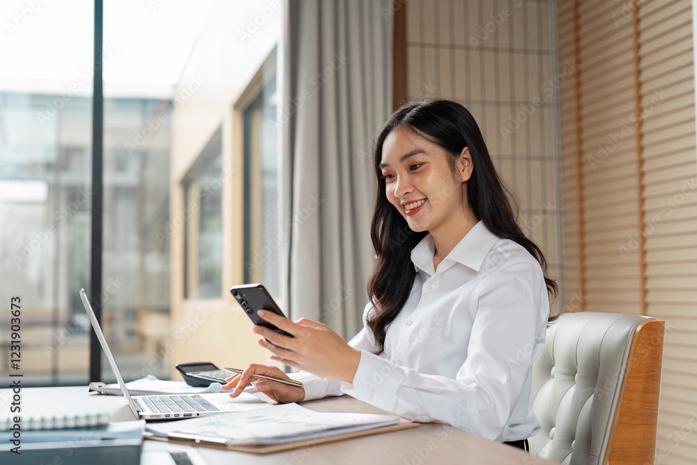 Smiling young woman using smartphone while working at modern office desk. Smiling young woman using smartphone while working at modern office desk.