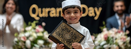 A young Muslim child stands proudly, holding an ornamental Quran in his hands
