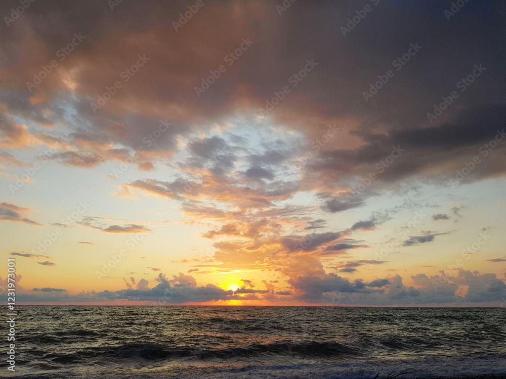 Obraz premium Colorful sky with dark clouds and bright sun light on sea beach