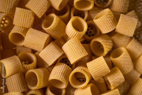 Golden, textured ditalini pasta in a close-up macro shot. Perfect for culinary blogs, Italian cuisine themes, and food-related designs. High-quality food photography with details of dry pasta. photo