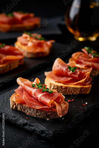 Pan con Tomate: Rustic bread slices brushed with ripe tomato, olive oil, and a pinch of salt, served with thin slices of Serrano ham on the side.