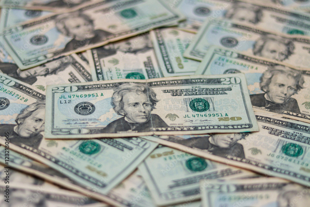 A collection of twenty dollar bills lies scattered across a surface, displaying intricate designs and green hues, illustrating elements of American currency. A collection of twenty dollar bills lies scattered across a surface, displaying intricate designs and green hues, illustrating elements of American currency.