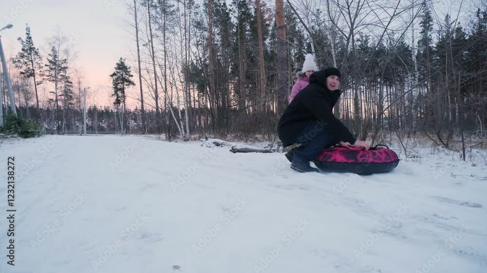 Child girls with dad riding snow tube on winter day. Funny games on winter vacation. Child girls with dad riding snow tube on winter day. Funny games on winter vacation.