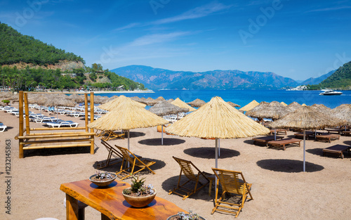 Tableau sur toile Tranquil beach in Icmeler with straw umbrellas and sun loungers