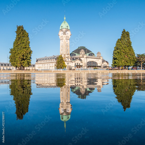 Square view of the train station in Limoges reflecting in blue water, France