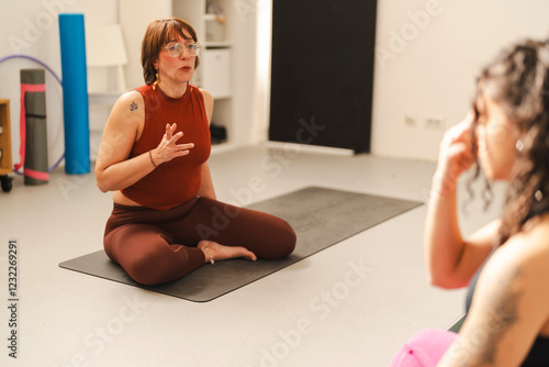 A yoga instructor demonstrating and guiding a student through pranayama breathing techniques in a well-lit home gym with modern furnishings and a calming environment. photo