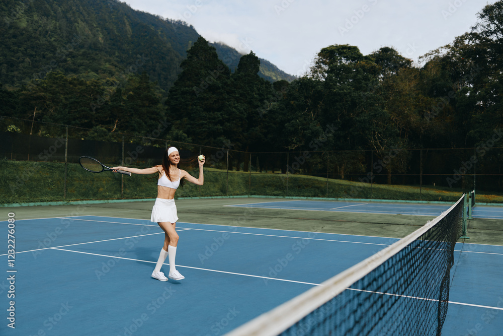 Obraz premium Young female tennis player celebrating on the court, wearing a sporty outfit, showcasing joy and energy in a vibrant outdoor setting with a lush green background