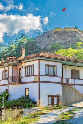 A historic Ottoman house with a Turkish flag atop a scenic hill. photo