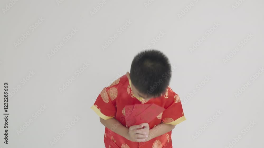 Smiling Asian boy in red cheongsam qipao holding a red envelope angpao, symbolizing good fortune during Chinese New Year. A vibrant portrait capturing tradition and joy. Isolated on white background. Smiling Asian boy in red cheongsam qipao holding a red envelope angpao, symbolizing good fortune during Chinese New Year. A vibrant portrait capturing tradition and joy. Isolated on white background.