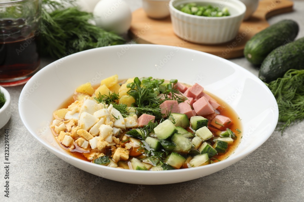 Delicious okroshka soup and ingredients on grey table, closeup Delicious okroshka soup and ingredients on grey table, closeup