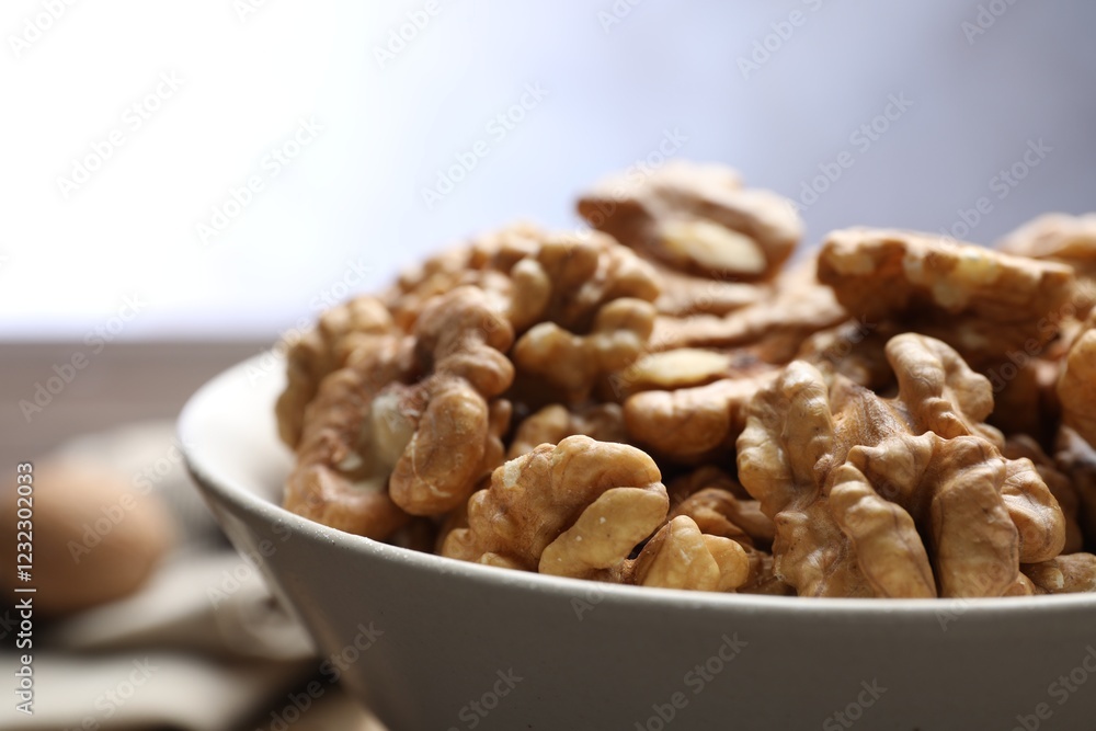 Peeled walnuts in bowl on table against light background, closeup Peeled walnuts in bowl on table against light background, closeup