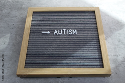 Autism written on a letter board with white tiles. Sunlight coming across