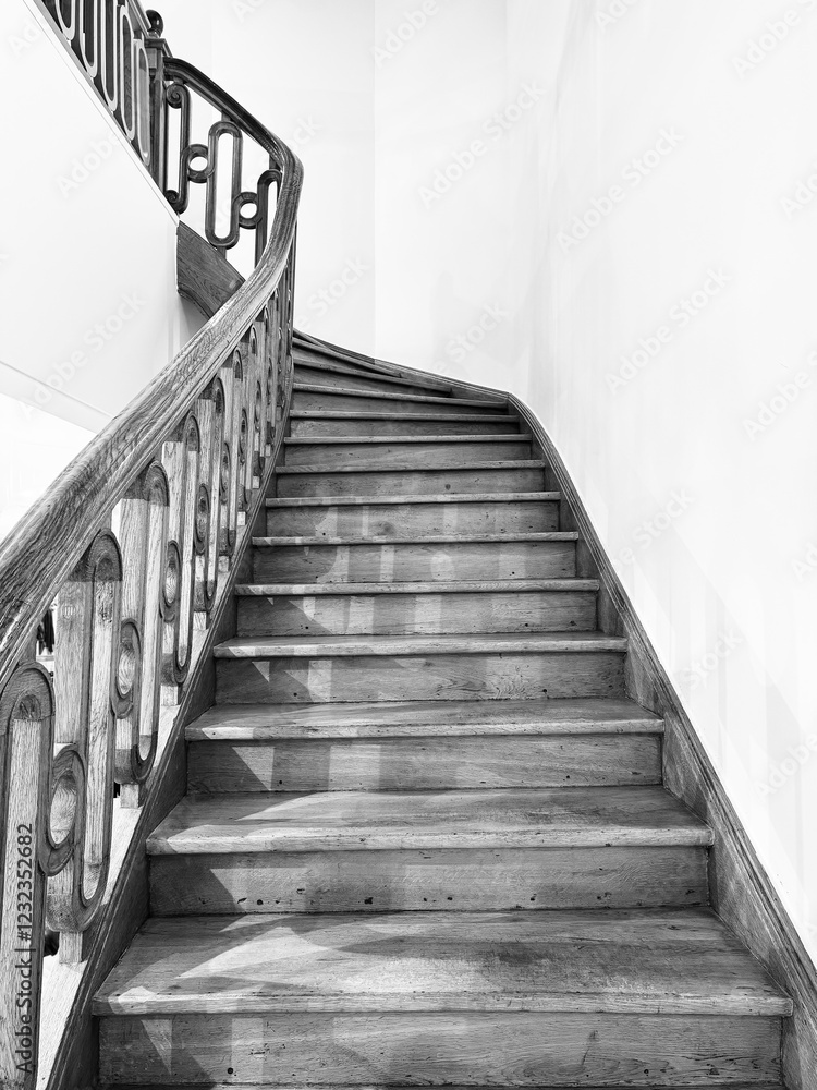 A wooden winding stairway in a stark white interior