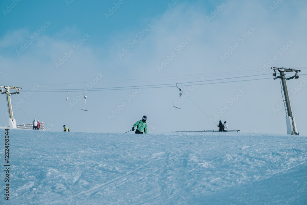A skier enjoying a snowy day on the slopes under a clear sky with ski lifts. A skier enjoying a snowy day on the slopes under a clear sky with ski lifts.