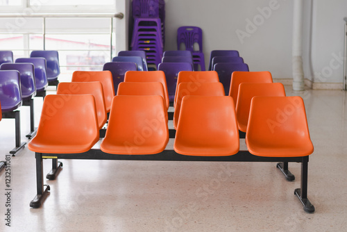 The seating arrangement in the public area consists of two rows of orange plastic chairs mounted on a black metal frame.