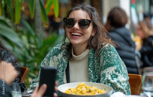 Young woman enjoying pasta at outdoor cafe in a lively urban setting during a...