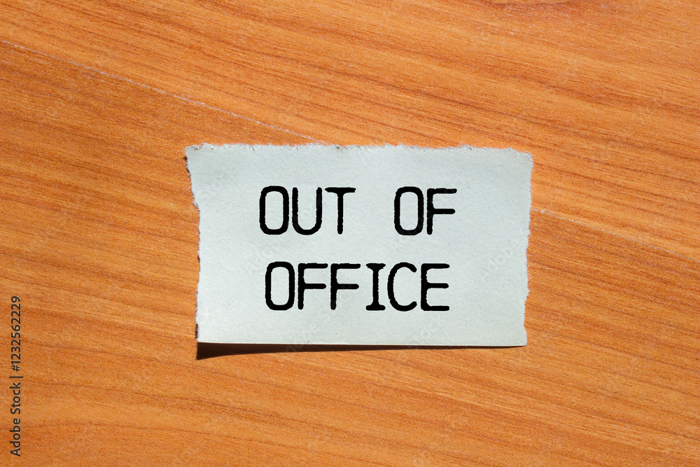 Out of office message written on ripped torn paper piece with wooden background. Conceptual out of office symbol. Copy space. Out of office message written on ripped torn paper piece with wooden background. Conceptual out of office symbol. Copy space.