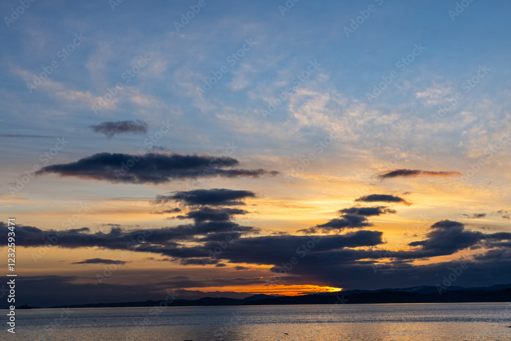 Naklejka premium Serene Sunset Over Vancouver Island Coastline with Vibrant Colors and Dramatic Clouds