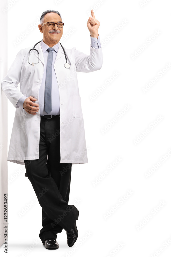 Mature male doctor leaning on a wall and pointing Mature male doctor leaning on a wall and pointing