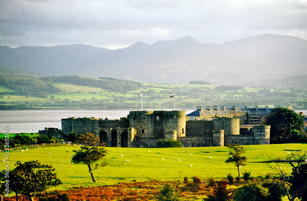 Beaumaris Castle visitor attraction, Anglesey, north Wales, UK with Menai Strait and mountains of Snowdonia behind