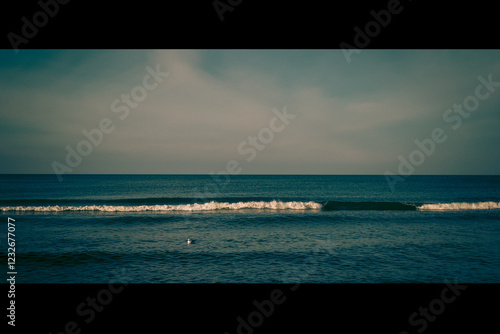 Fototapeta Naklejka Na Ścianę i Meble -  Calm beach on the Baltic Sea in the warm light of sunset. Gentle waves, sandy coastline and subtle atmosphere of relaxation. Perfect image for themes related to nature, travel, and holidays.