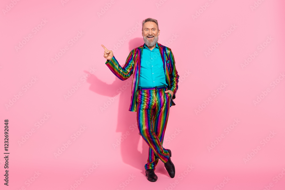 Senior stylish man in vibrant suit pointing on pink background Senior stylish man in vibrant suit pointing on pink background