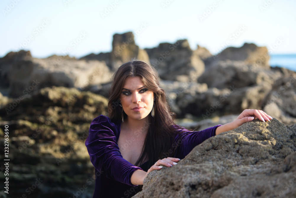 beautiful young woman dancing flamenco among the rocks by the seashore, wearing a purple velvet dress with ruffles. The gypsy woman makes different expressions with her face and hands. beautiful young woman dancing flamenco among the rocks by the seashore, wearing a purple velvet dress with ruffles. The gypsy woman makes different expressions with her face and hands.
