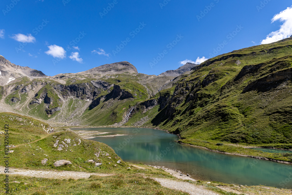 Fototapeta premium The Grossglockner mountain range in Austria with a winding road leading to the lake.