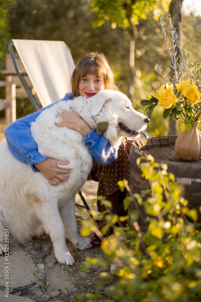 A joyful woman hugging her Maremma dog in a rustic garden, surrounded by yellow flowers and bathed in warm sunlight. A heartwarming scene of love, companionship, and rural charm A joyful woman hugging her Maremma dog in a rustic garden, surrounded by yellow flowers and bathed in warm sunlight. A heartwarming scene of love, companionship, and rural charm