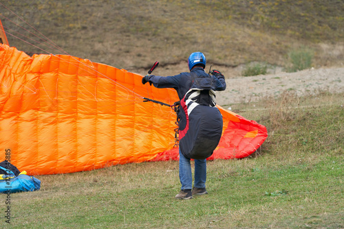 Paraglider landing. The pilot put the canopy on the ground and untangles the slings. photo