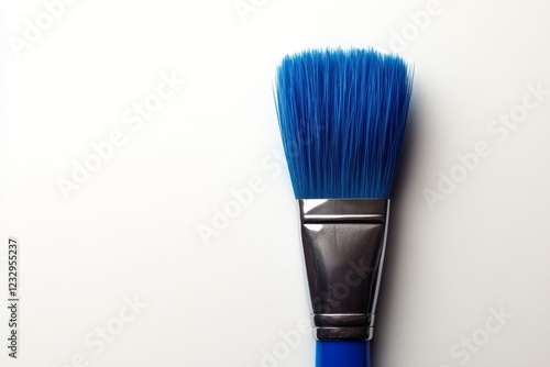 Artistic blue paint brush resting against a light background showcasing vibra...