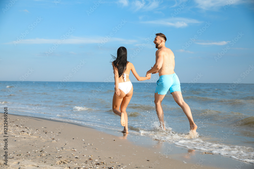 Happy young couple running together on beach Happy young couple running together on beach