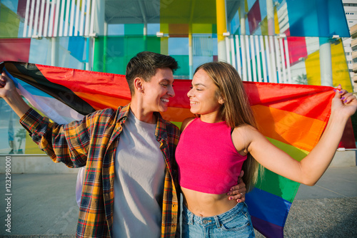 Happy lesbian couple embracing with pride flag outdoors photo