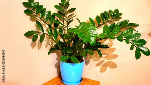 A plant in a blue pot sits on a wooden table