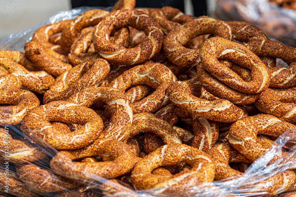 A large pile of golden-brown simits, traditional Turkish bagels, fills a clear plastic bag. The sesame-seeded rings are freshly baked, appealing and delicious-looking. Perfect for food blogs A large pile of golden-brown simits, traditional Turkish bagels, fills a clear plastic bag. The sesame-seeded rings are freshly baked, appealing and delicious-looking. Perfect for food blogs