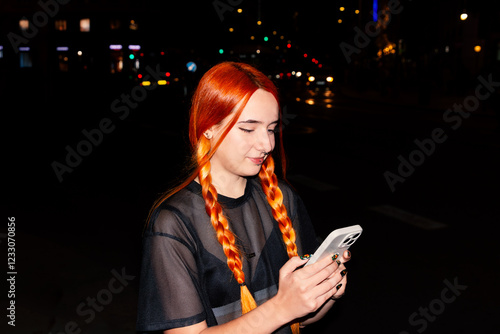 Woman with braided hair using smartphone at night in city photo