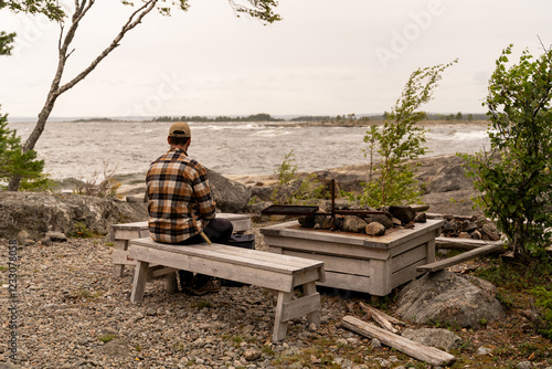 Man enjoying a serene coastal view from a rustic bench photo