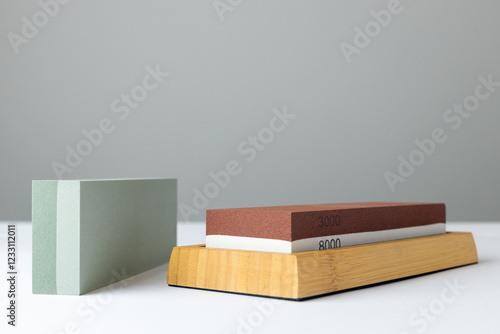 closeup white background on table lies all the equipment a set for sharpening and polishing kitchen knives and various blades different abrasiveness of stones a retainer for knives