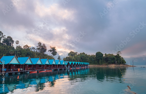 Floating village huts with incredible view of Cheow Lan Lake, surrounded by rainforest jungle and evening clouds. Stunning scenery in Surat Thani Province, Thailand. photo