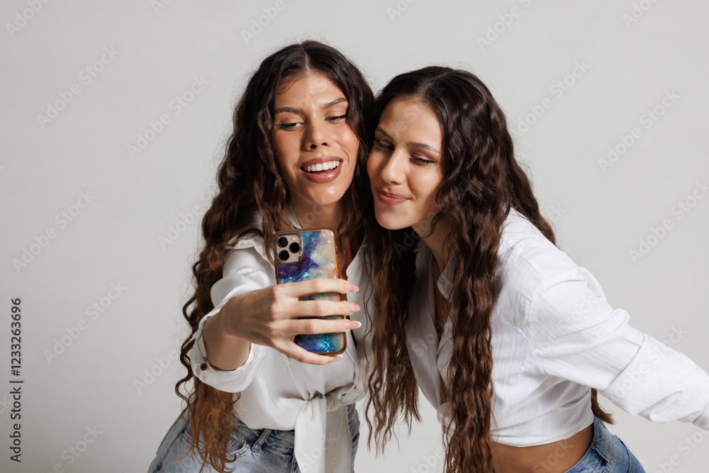 Two joyful young women capturing a selfie together while smiling and having fun Two joyful young women capturing a selfie together while smiling and having fun