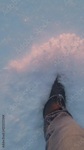 Walking in snow. Legs of man walking on snow in sunlight.