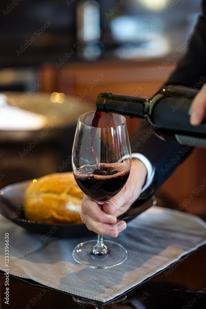 Obraz premium Hand Pouring Red Wine Into an Empty Glass
